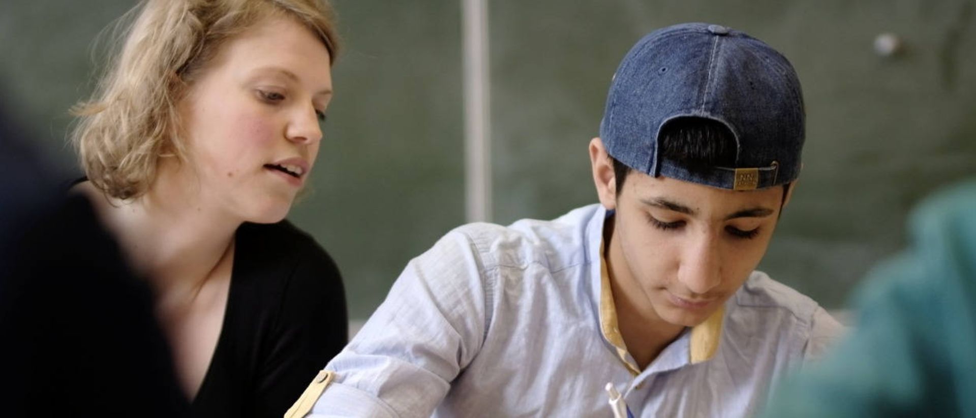 A college graduate helps a student with his assignments.