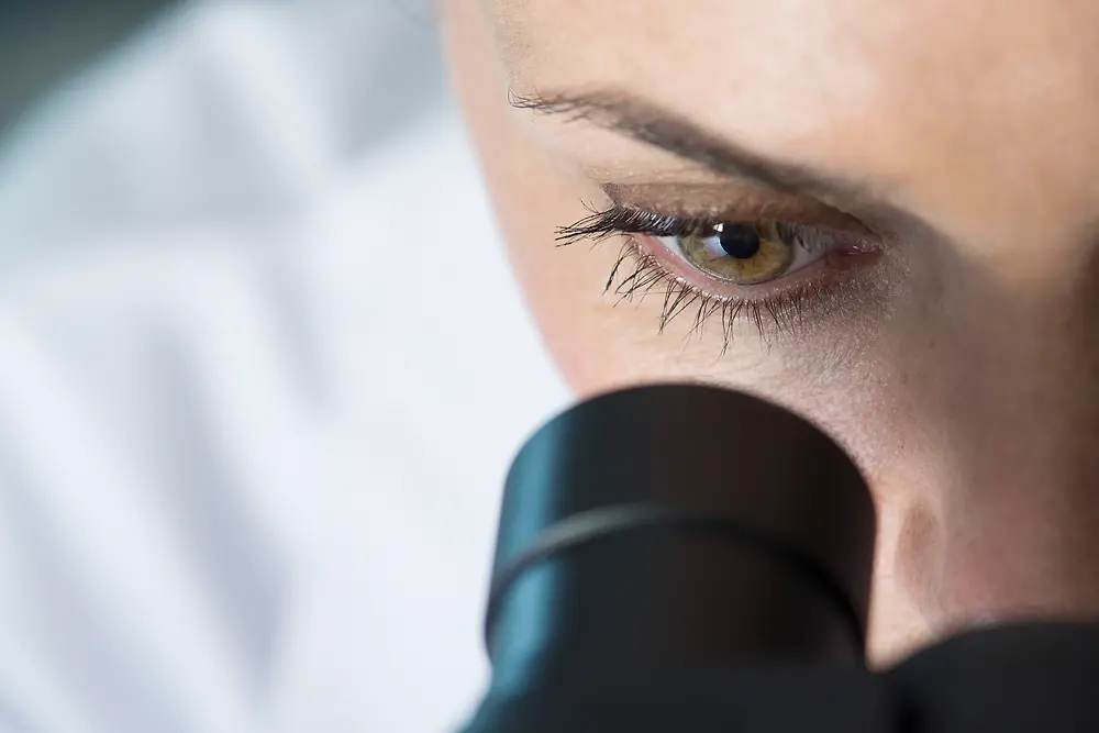 L'occhio di una donna che guarda in un microscopio