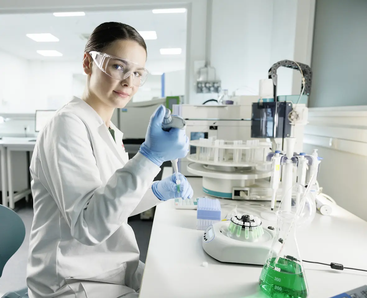 Una scienziata con camice e occhiali di sicurezza fa esperimenti in laboratorio