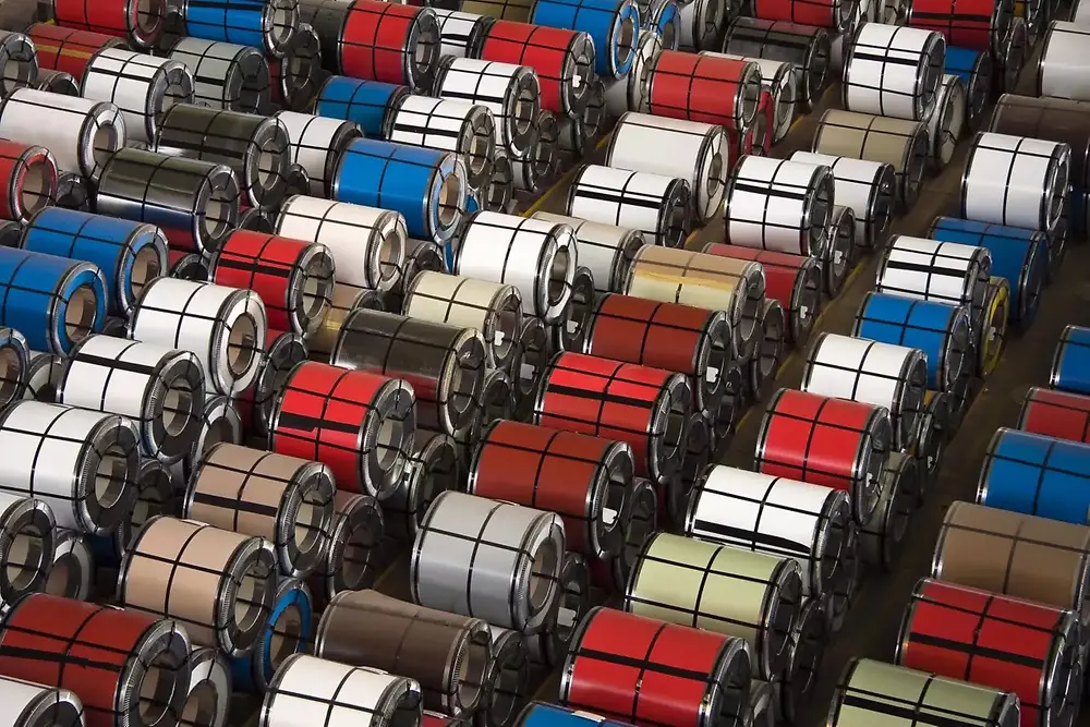 Vista ravvicinata di bobine di metallo impilate in un magazzino industriale.