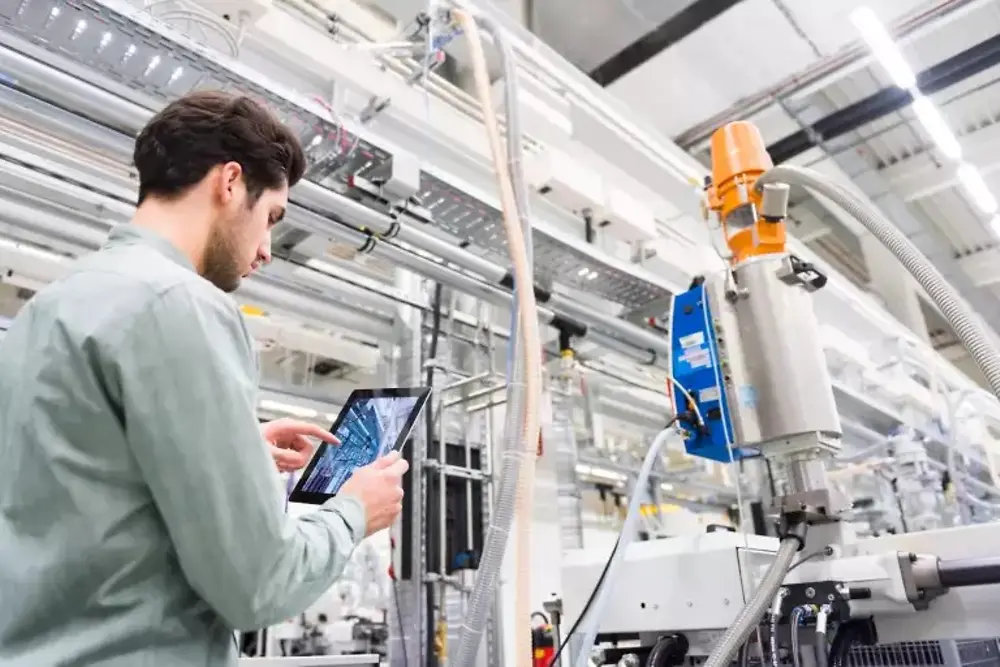 Operai che azionano macchinari all'interno di uno stabilimento di produzione industriale.