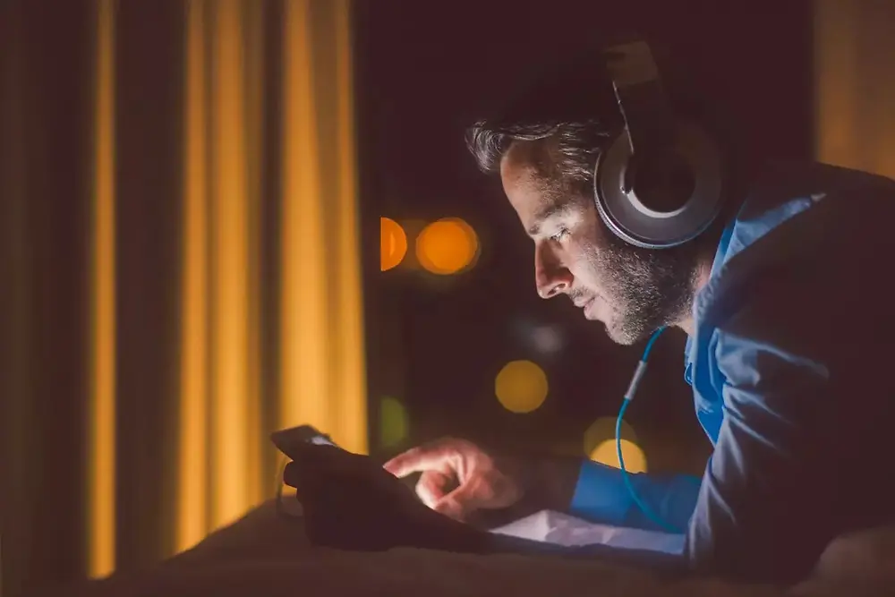 Persona con le cuffie che lavora con apparecchiature elettroniche in un ambiente buio.