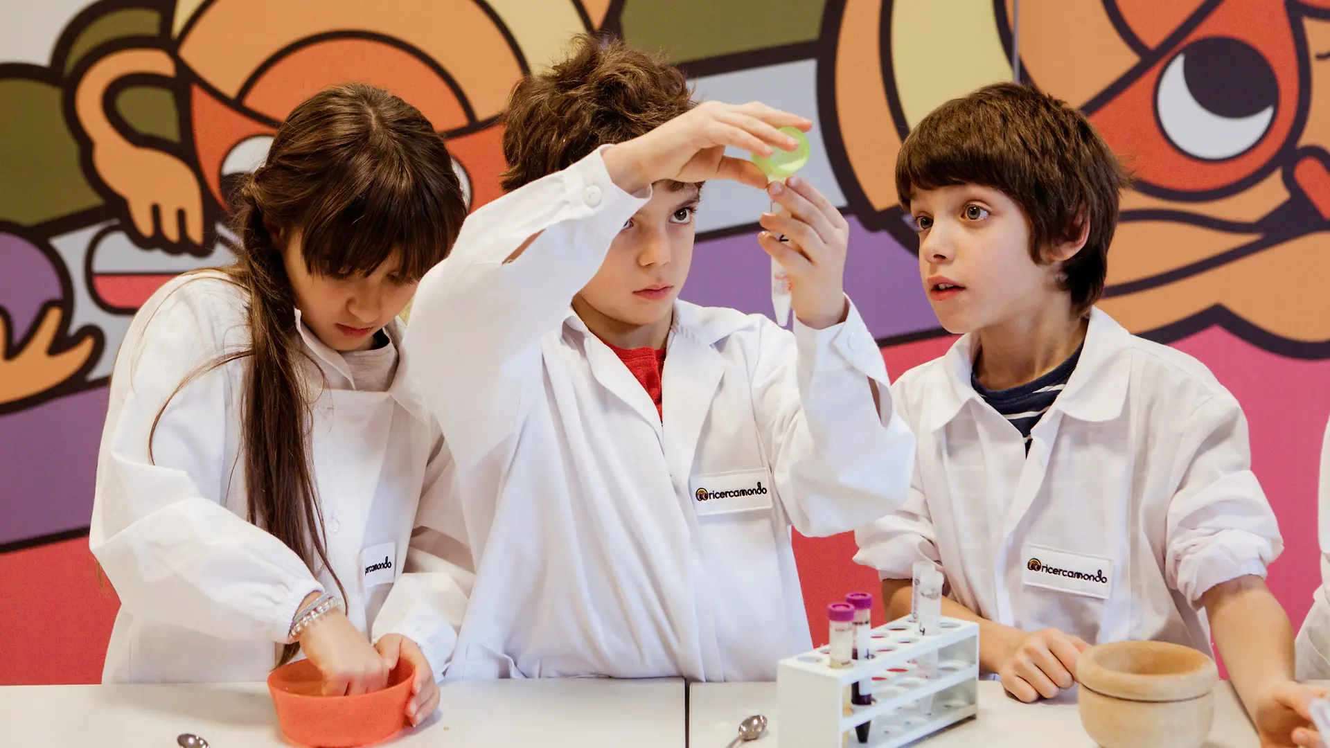 Due piccoli scienziati e una piccola scienziata curiosi durante i laboratori di Ricercamondo