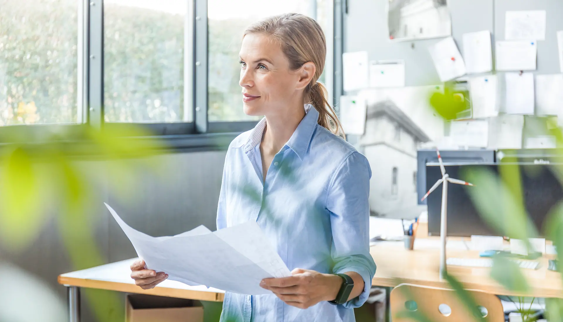 Woman in office working on plan with wind turbine model on table
