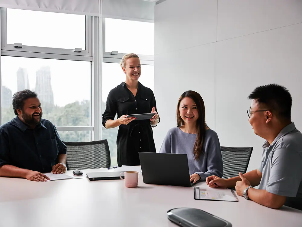 Un gruppo eterogeneo di professionisti e professioniste collabora in una moderna sala riunioni attorno a un tavolo con computer portatili e documenti. La scena riflette l'impegno di Henkel per l'equilibrio di genere e la diversità nella leadership, valorizzando un ambiente di lavoro inclusivo in cui prospettive diverse contribuiscono ai processi decisionali.