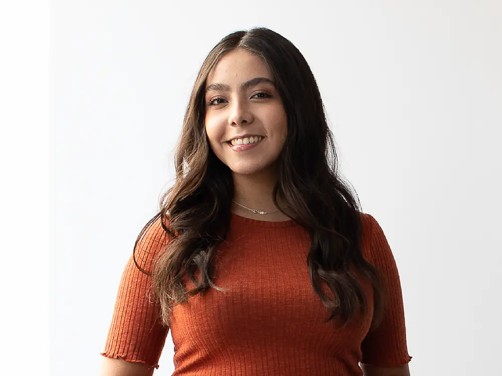 Talent Acquisition Manager in Messico che indossa una maglia a maniche corte a coste arancione e condivide approfondimenti su come distinguersi su LinkedIn.