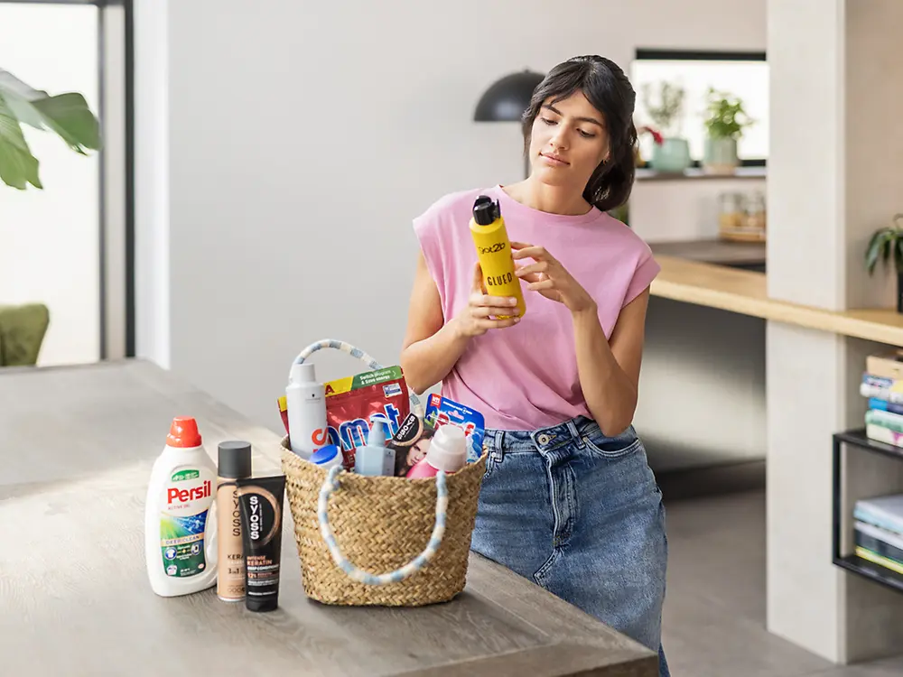 Donna con una selezione di prodotti per cura della casa, del bucato e dei capelli. 