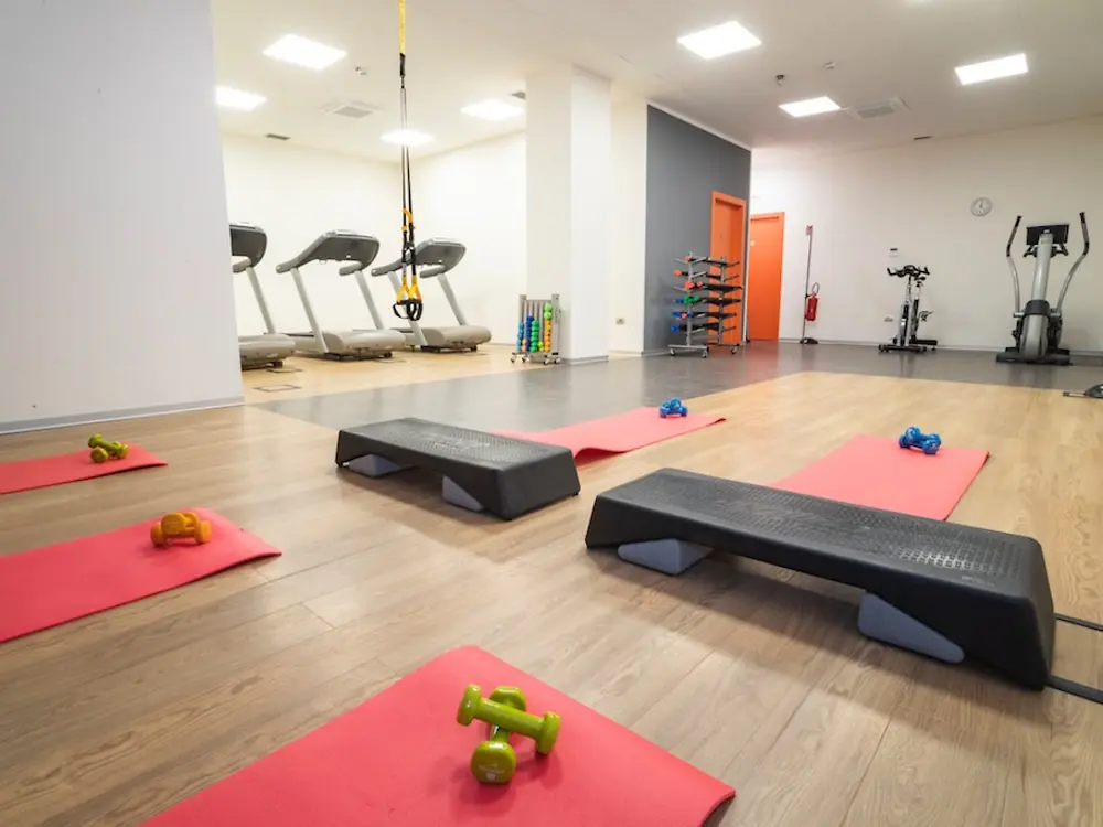 Palestra aziendale attrezzata con area functional training, tappetini, step e macchine cardio